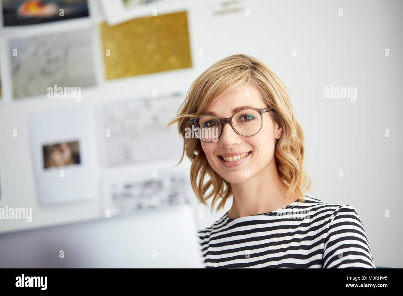 Ritratto di sorridere donna bionda, bicchieri, pc Foto Stock