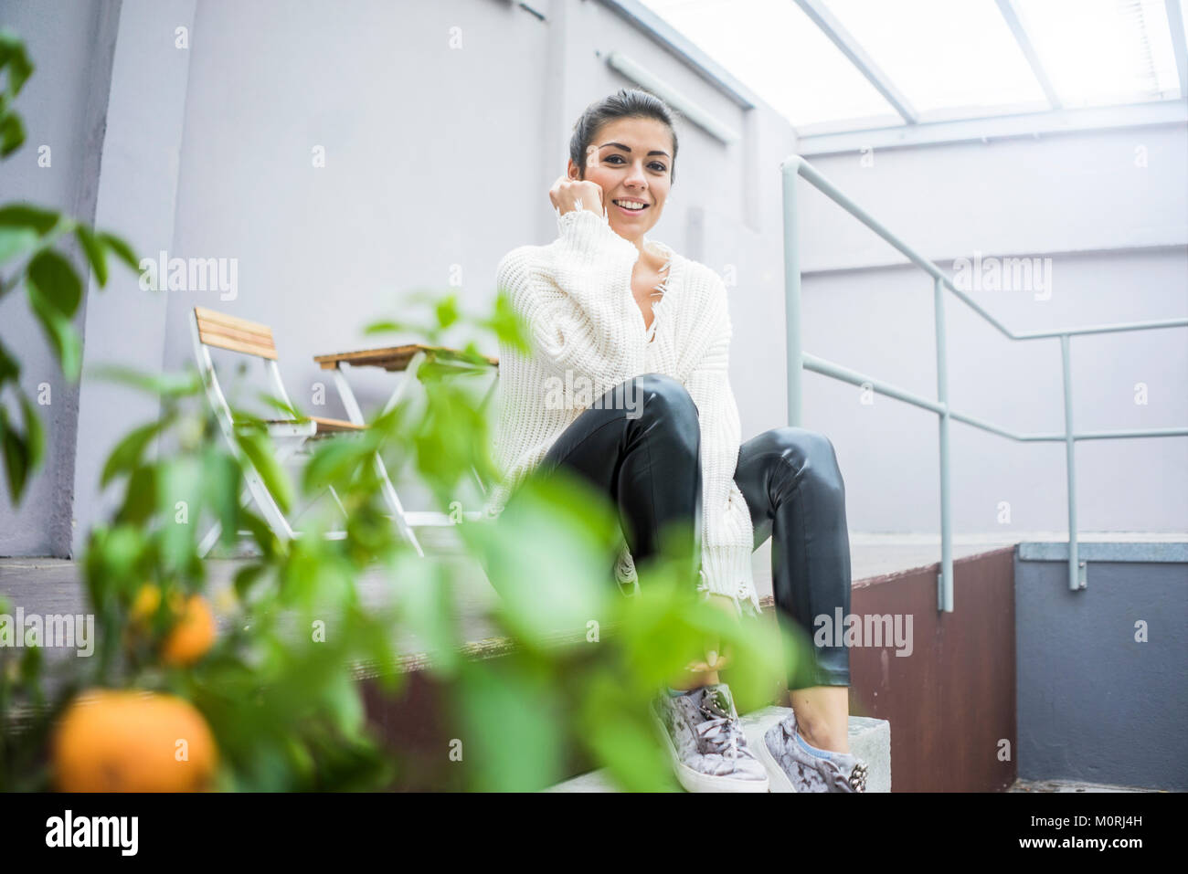 Ritratto di felice giovane donna seduta sulla terrazza Foto Stock