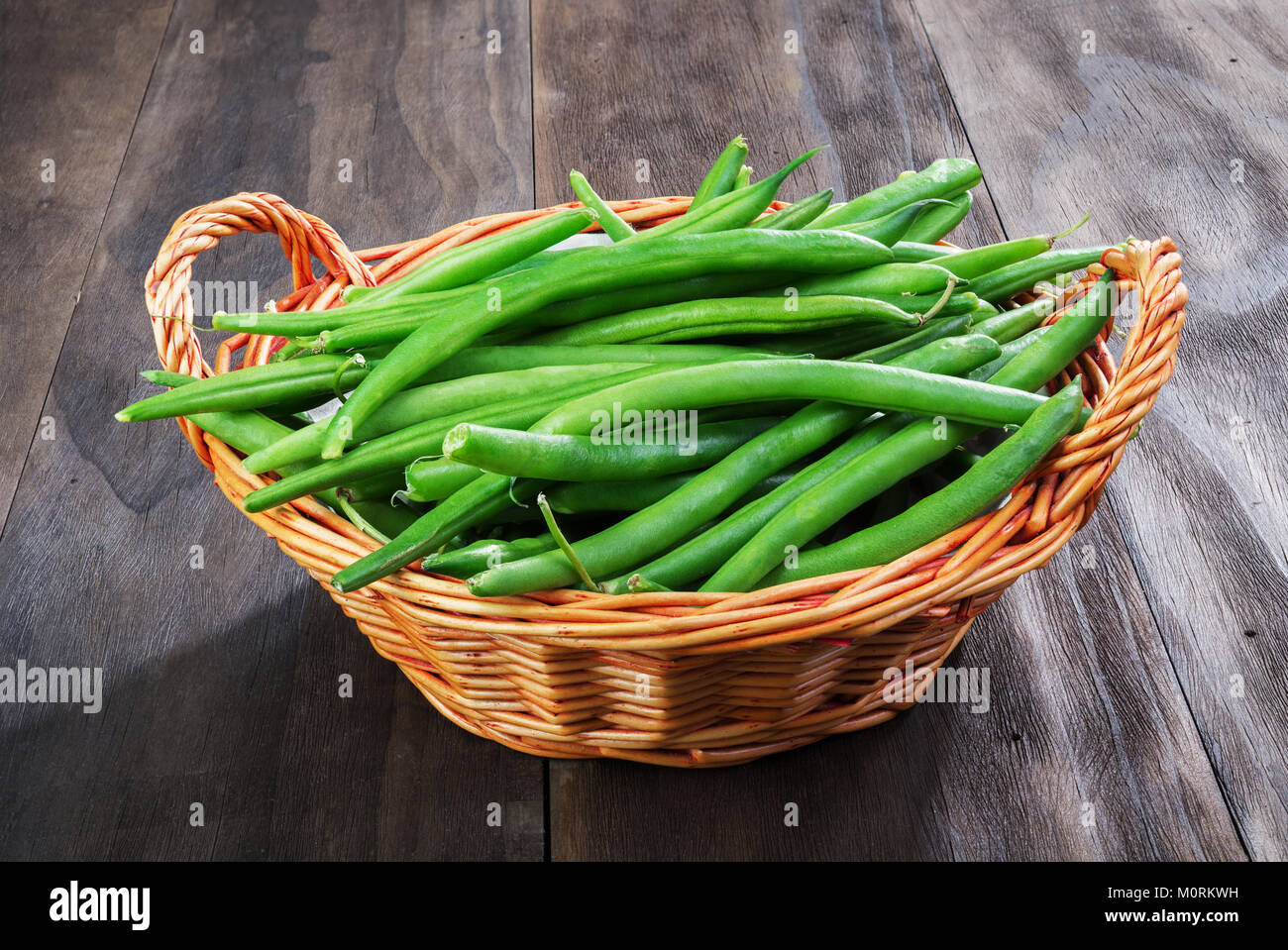 Fagioli verdi stringa nel cesto di vimini su un vecchio legno sfondo nero.Vista dall'alto. Foto Stock