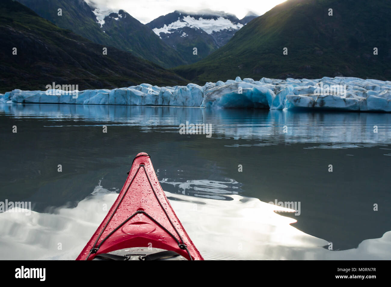 Un rosso kayak in flottante il terminale lago del ghiacciaio Spencer punti verso il parto faccia terminale del ghiacciaio e una piccola valle del moun Foto Stock
