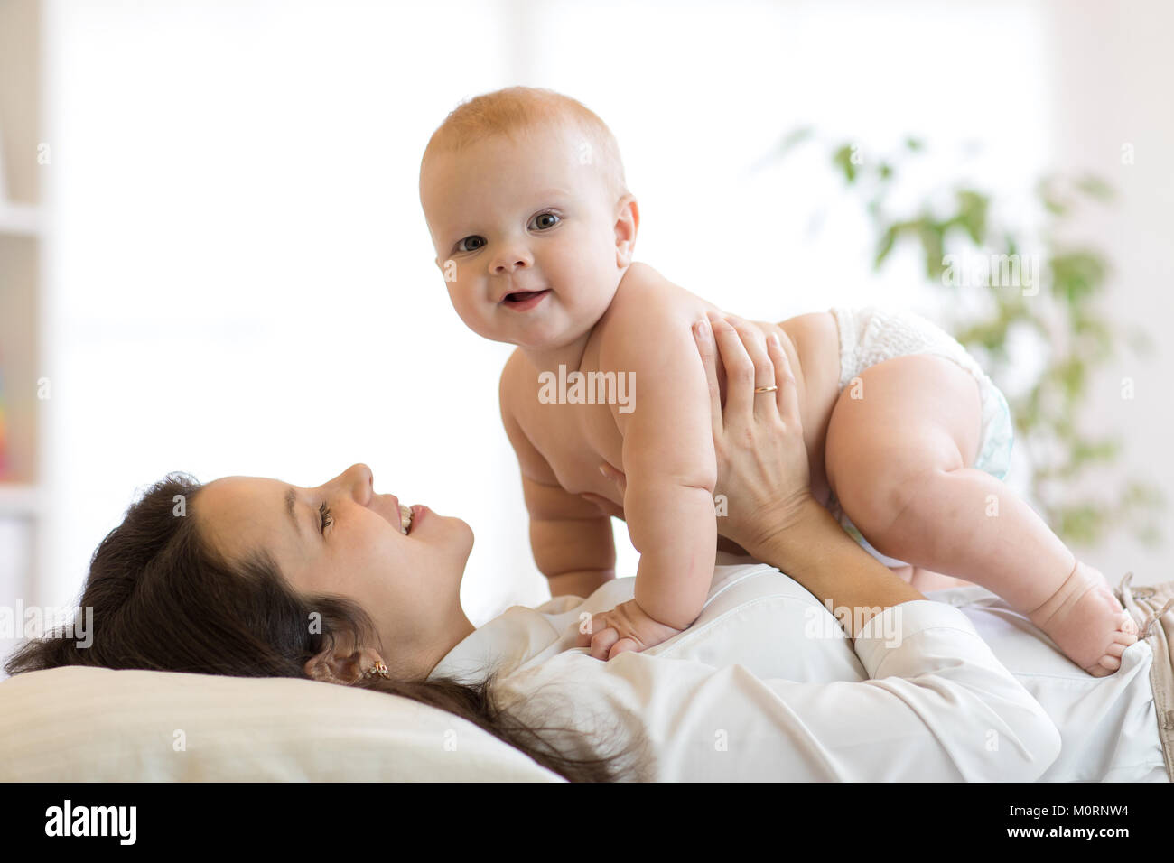 La madre e il bambino a giocare nella soleggiata camera da letto. Genitore e bambino in un momento di relax a casa. Famiglia avente divertimento insieme. Foto Stock