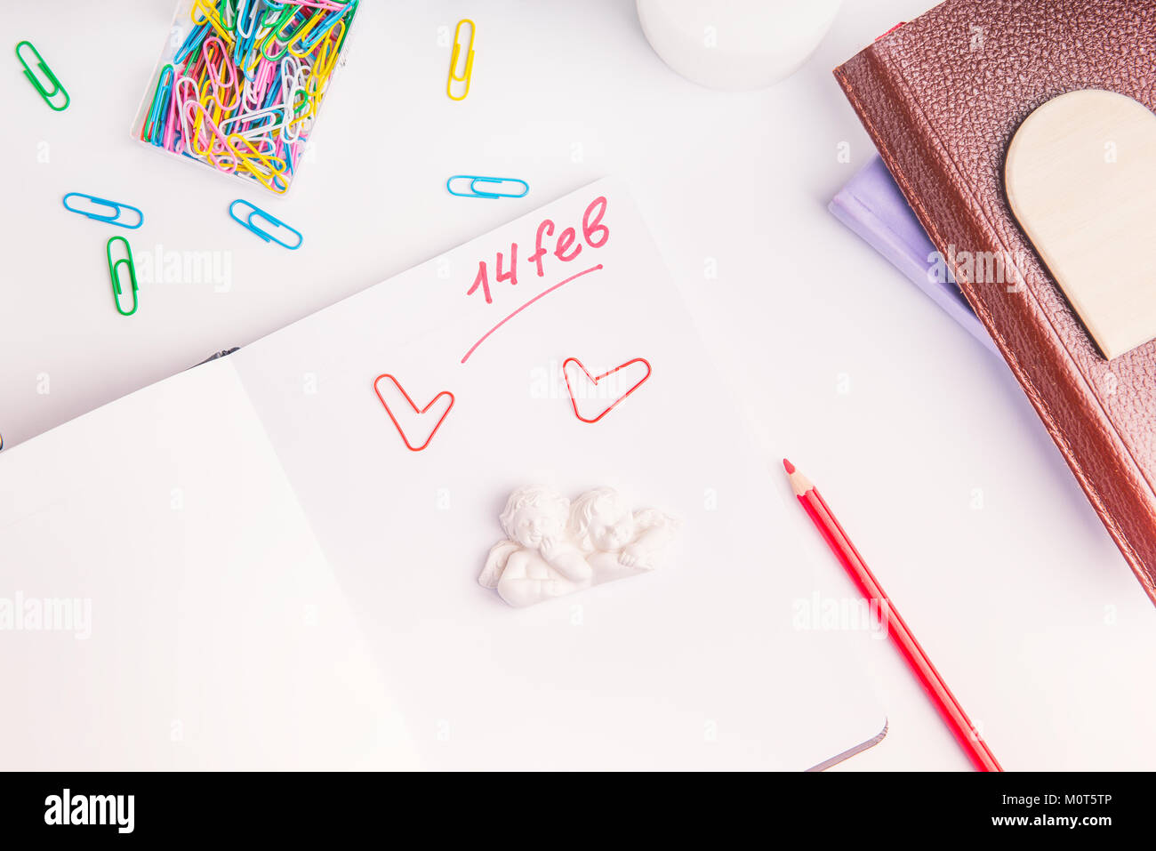 Rosso numero della grafia quattordici febbraio, San Valentino testo e angeli stauette su agenda elettronica personale sul luogo di lavoro. Il giorno di San Valentino il concetto di pianificazione. Messa a fuoco selettiva. Foto Stock