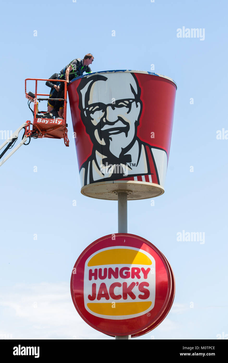 Un uomo che pulisce un gigante KFC segno della benna Foto Stock