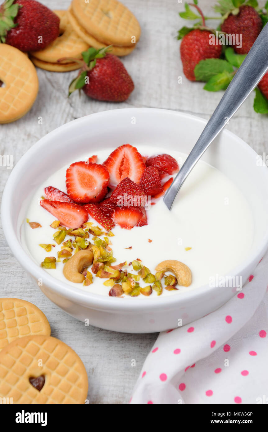 Refrigerate latticello zuppa da yogurt greco con le fragole e i pistacchi anacardi. Servire con biscotti croccanti. Colpo verticale. Foto Stock