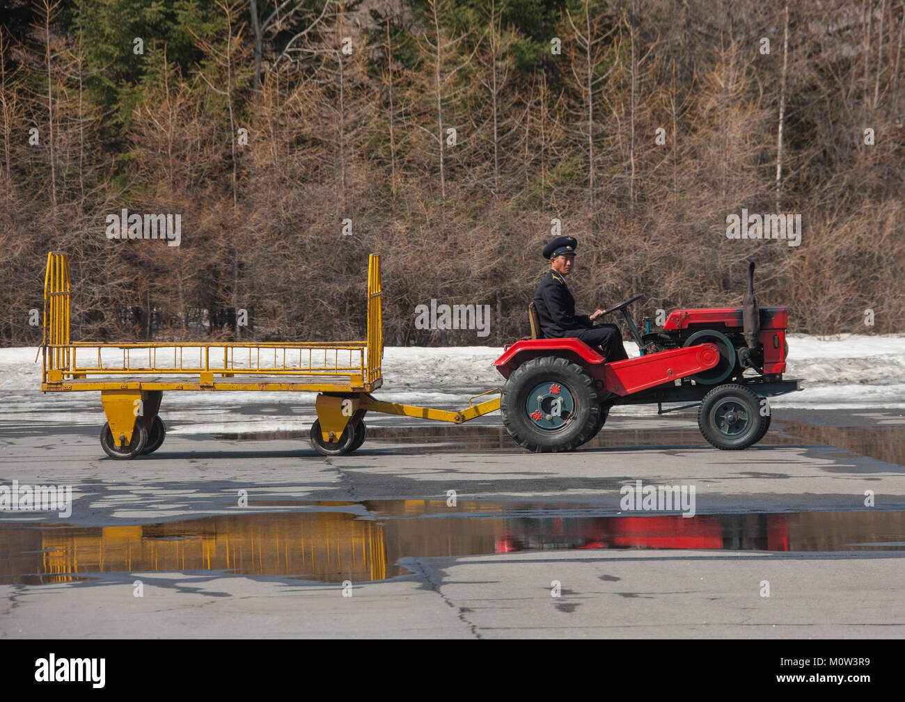 Il trattore e il rimorchio conducente a Samjiyon airport airfield andando a prelevare i turisti bagagli, Ryanggang Provincia, Samjiyon, Corea del Nord Foto Stock