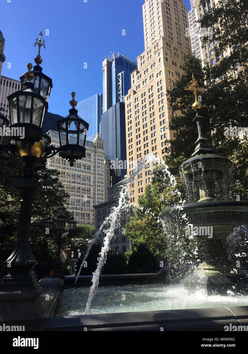 Visualizzare fino al cielo azzurro e imponenti grattacieli di Manhattan da una fontana in City Hall Park Foto Stock