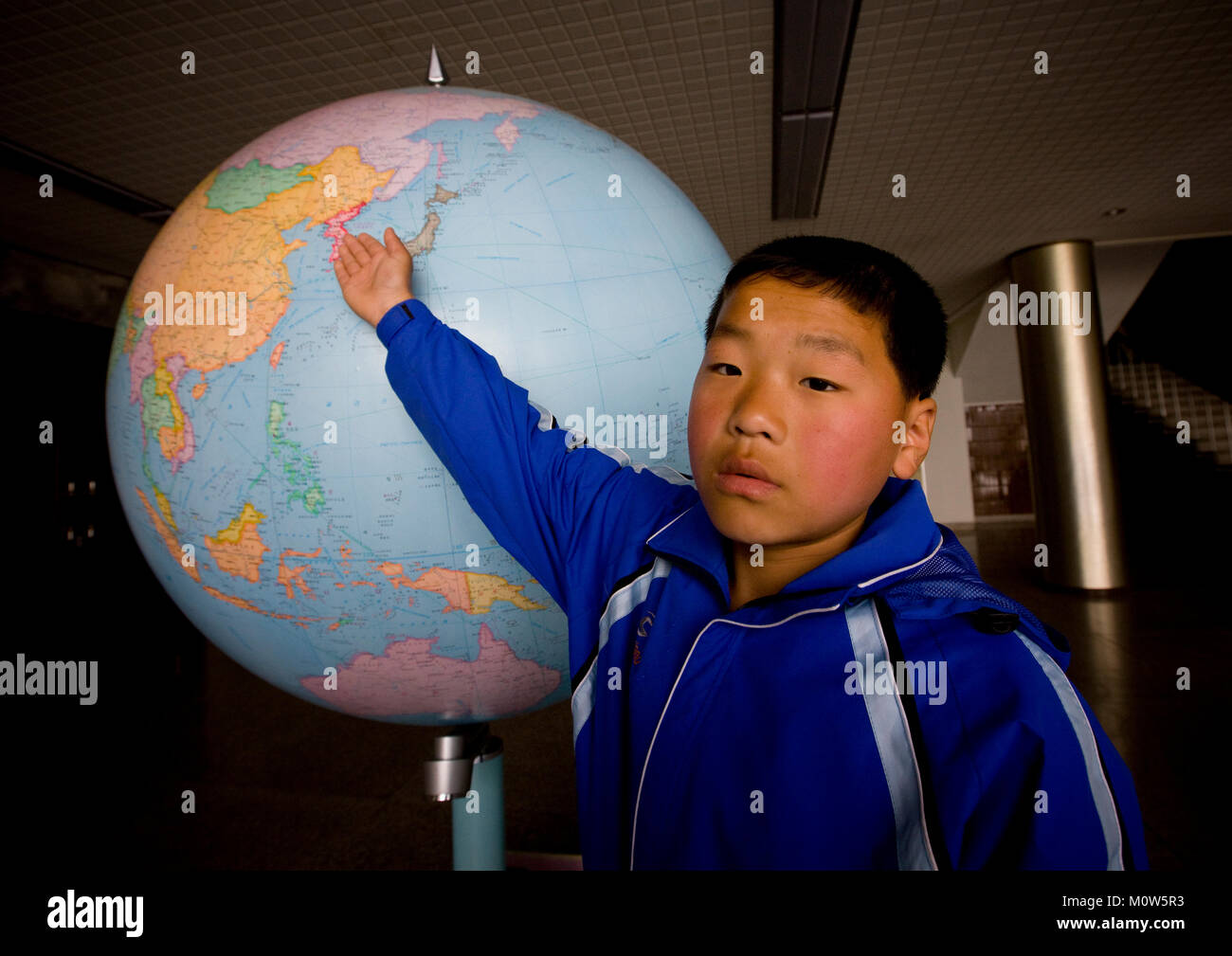 North Korean boy che mostra la Corea del Nord su una mappa del mondo in Songdowon internazionale dei bambini camp, Kangwon Provincia, Wonsan, Corea del Nord Foto Stock