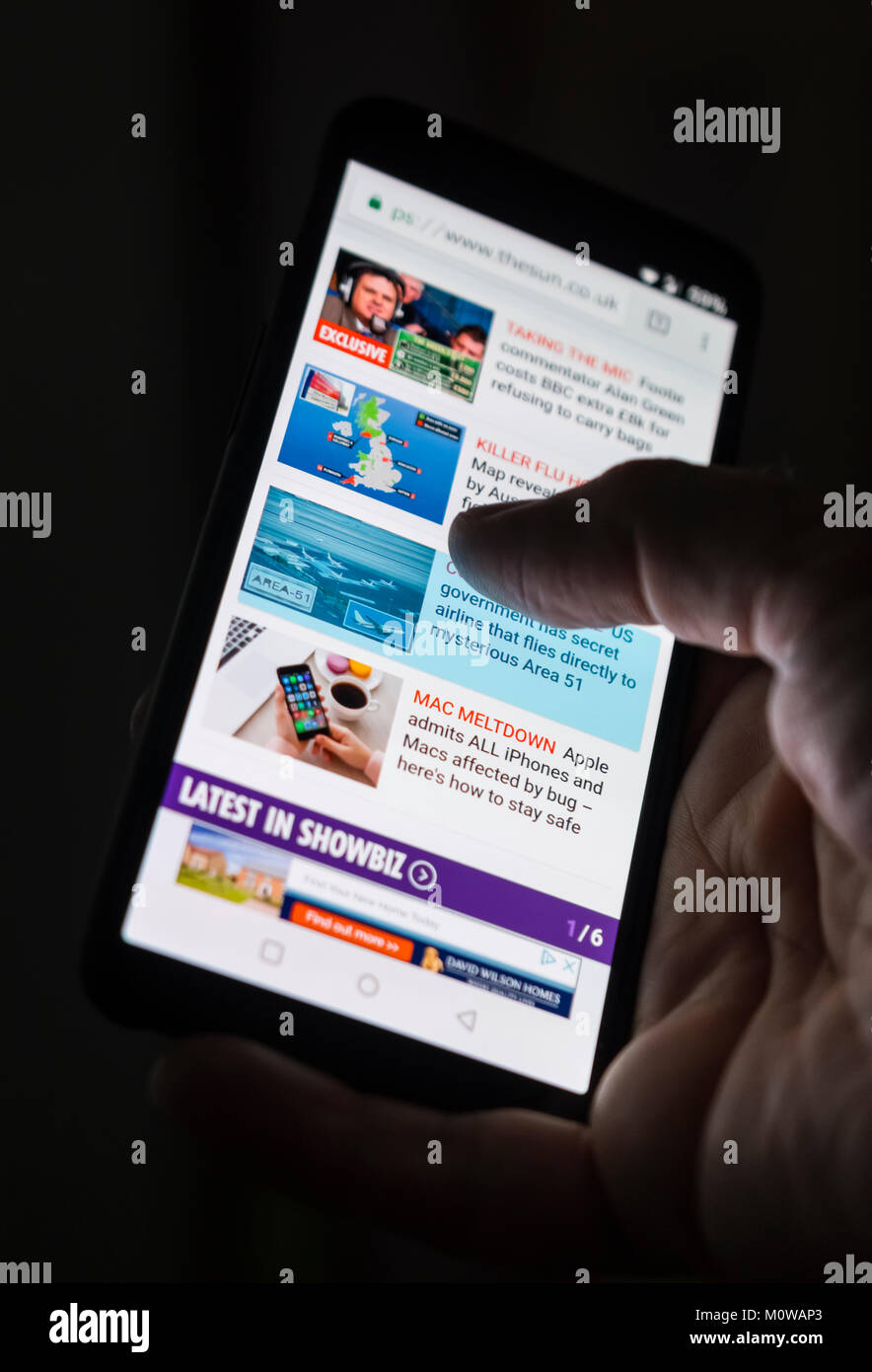 La lettura di notizie su Internet utilizzando uno smartphone. Foto Stock