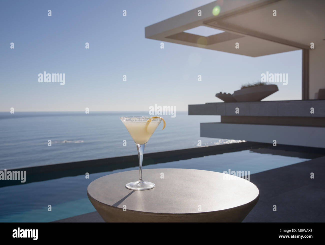 Limone cocktail Martini in vetro sul soleggiato patio di lusso con vista oceano Foto Stock