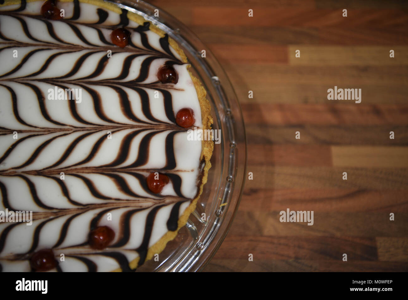Fotografia di cibo di una casa fatta Bakewell tart torta con pasta frolla  frangipane e mandorle con un pattern di cioccolato topping ghiacciato e  ciliegie Foto stock - Alamy