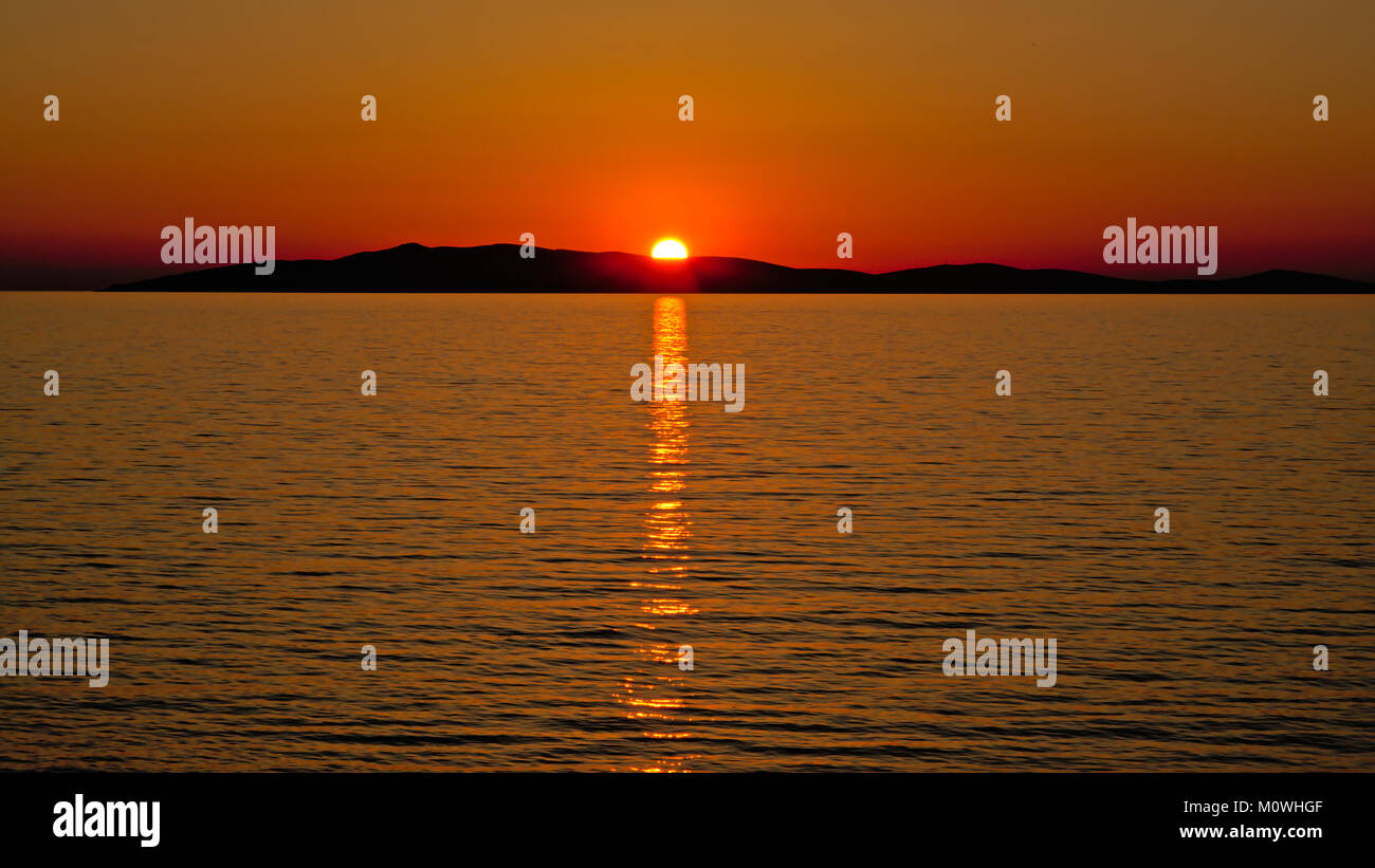 Caldo arancio tramonto sopra la silhouette di un'isola nel mare Adriatico, vista dalla spiaggia di Mali Losinj, Croazia Foto Stock