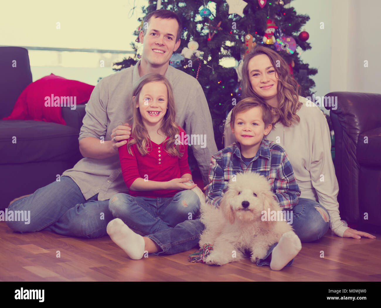 I genitori e i bambini che posano per una foto di albero di Natale a casa Foto Stock