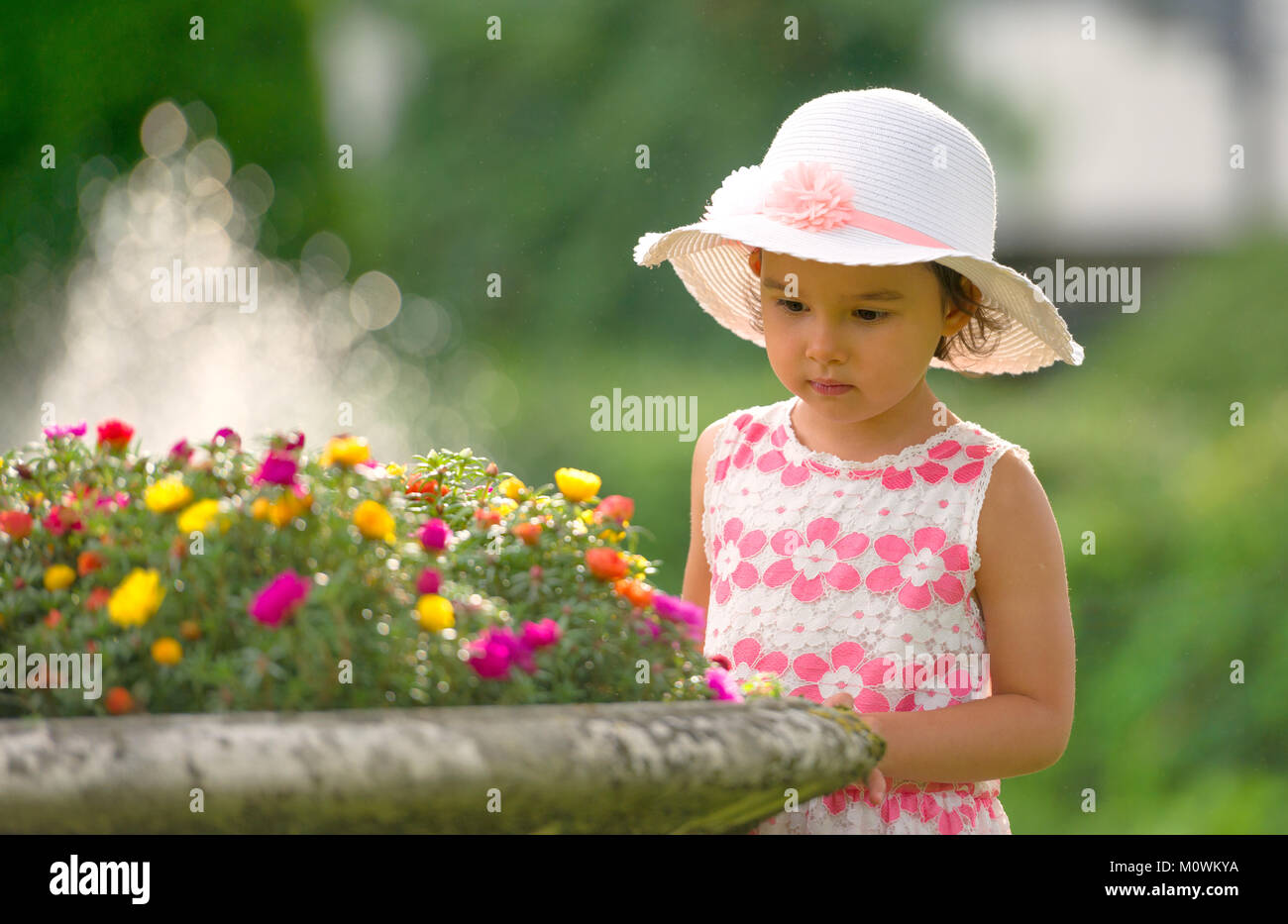 Bambina nel giardino ammirando fiori Foto Stock