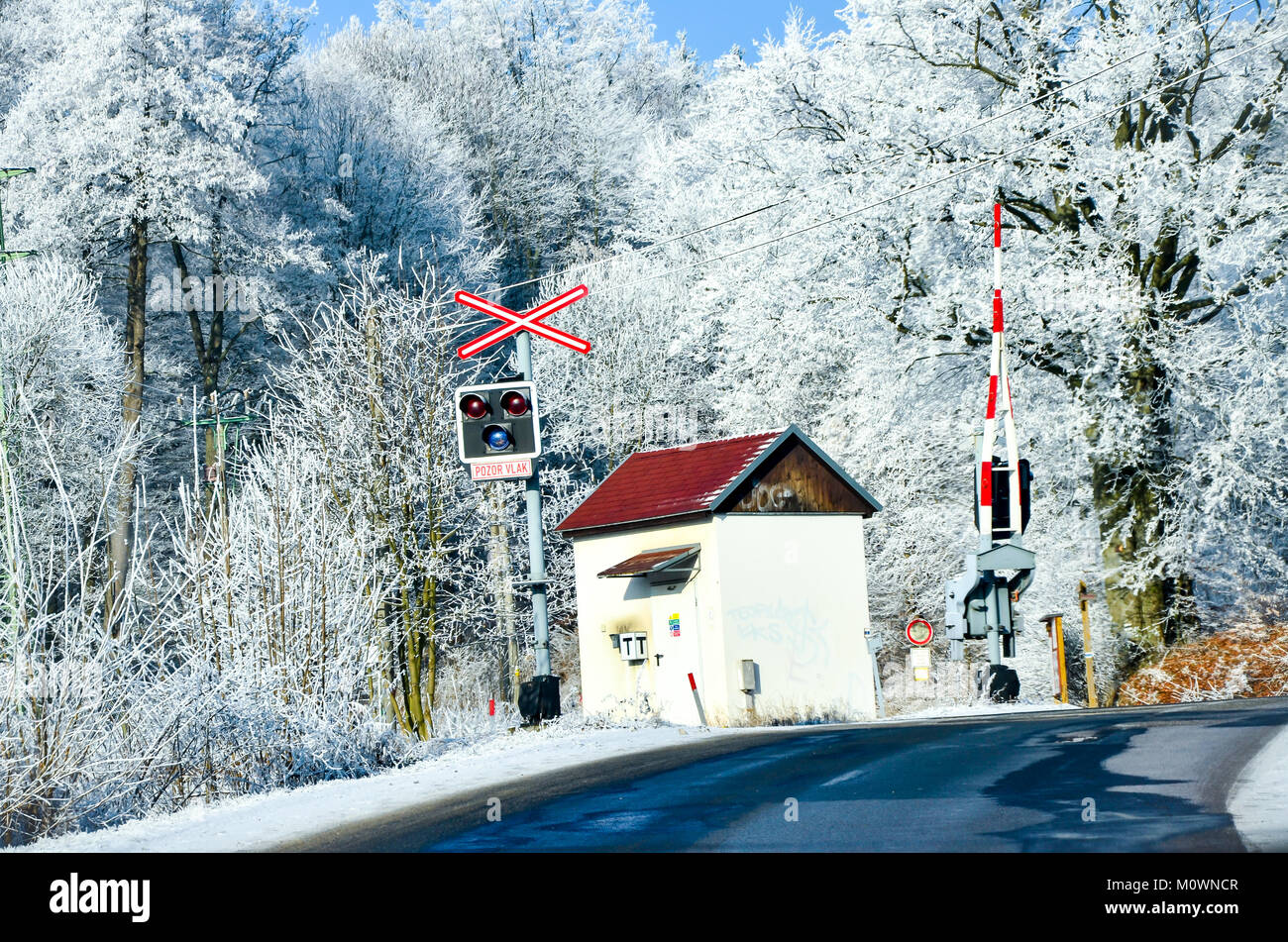 Strada con il passaggio a livello e le barriere in inverno utilizzabile per le informazioni sul traffico con spazio libero per il testo Foto Stock