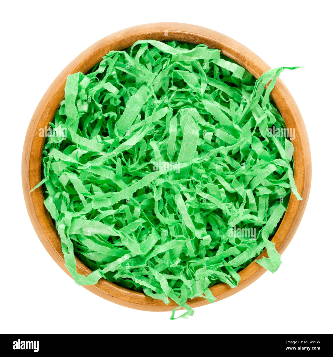 Libro verde erba di Pasqua nella ciotola di legno formando un nido. Colori vibranti e zigrinato cesto regalo shred per il riempimento e la decorazione. Foto Stock