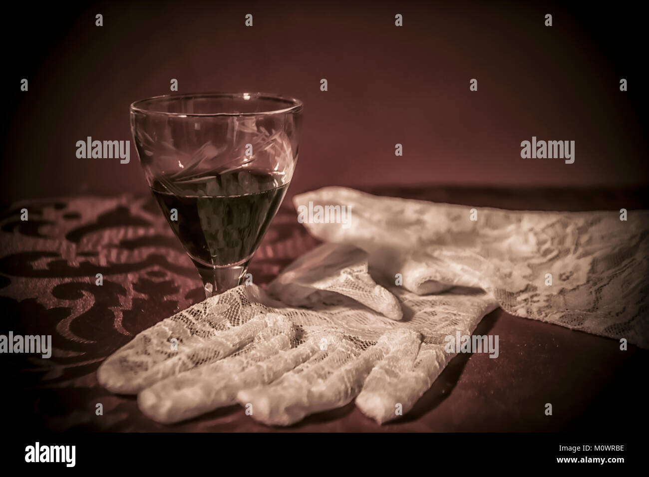 Bianco guanti di pizzo e un bicchiere di cherry brandy Foto Stock