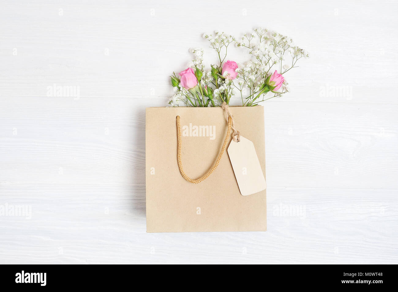 Mock up composizione sacchetto di carta e tag di fiori bianchi in stile rustico, per il giorno di San Valentino con un posto per il vostro testo. Piatto, laici top view photo mock up Foto Stock