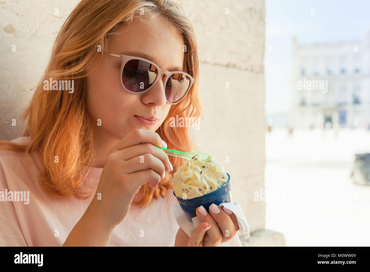 Europeo teenage girl in occhiali da sole mangia frutta gelato, closeup ritratto all'aperto Foto Stock