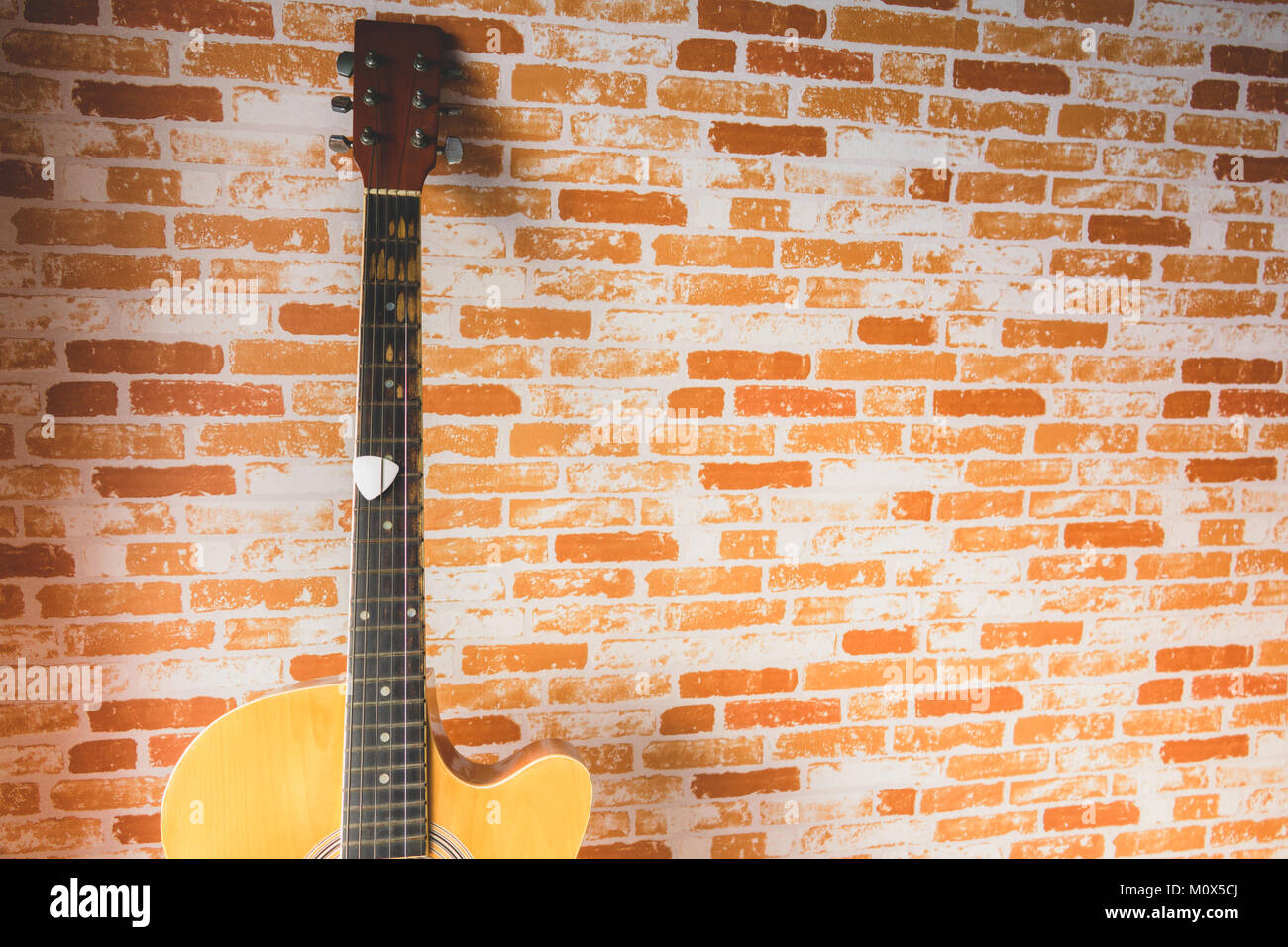 Plettro bianco di chitarra su chitarra acustica con mattoni blackground Foto Stock