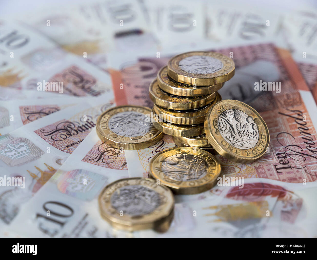 Un mucchio di nuove British pound monete su una frontura circolare di nuovo dieci Pound sterling note Foto Stock