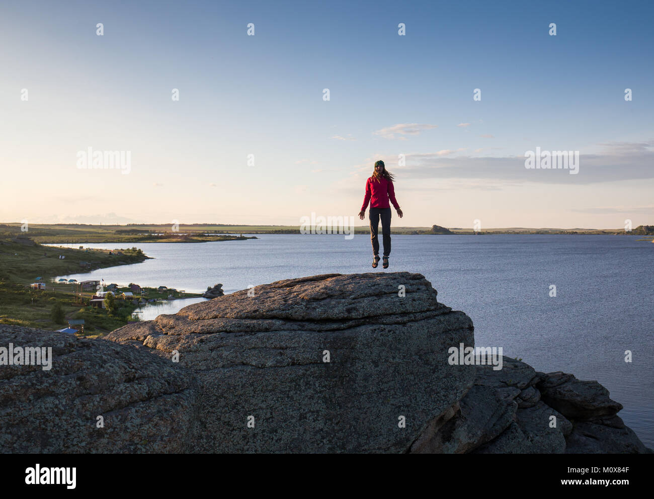 Giovane donna seduta su roccia e gode di splendida vista Foto Stock