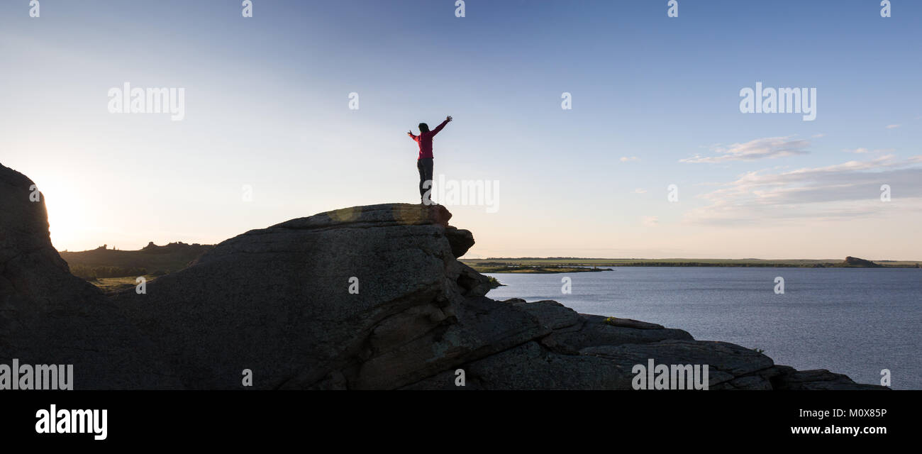 Giovane donna seduta su roccia e gode di splendida vista Foto Stock