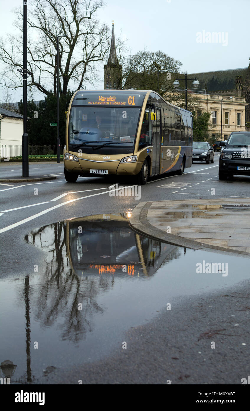 Stagecoach bus oro riflesso in una pozzanghera, Leamington Spa, Regno Unito Foto Stock