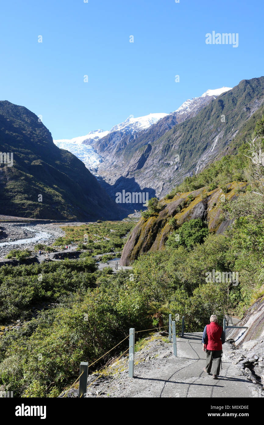 Walker sul sentiero al ghiacciaio Franz Josef in Westland Tai Poutini national park, South Island, in Nuova Zelanda con il fiume Waiho nel fondo valle. Foto Stock