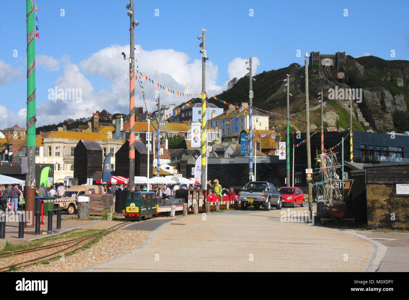 Un paesaggio di sole foto di stile di Stade nella storica città vecchia HASTINGS,UK con East Hill e treno in miniatura visibili e cielo blu Foto Stock