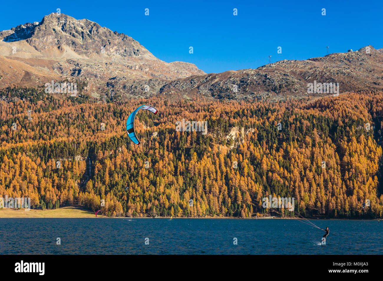 Wind surf sul lago di Silvaplana con la caduta delle foglie colore in larice alberi in Engadina, Graubuden, Svizzera, Europa. Foto Stock