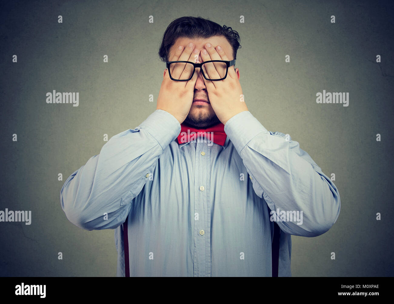 Chunky uomo in abbigliamento formale e occhiali che coprono gli occhi con le mani cercando stanco. Foto Stock