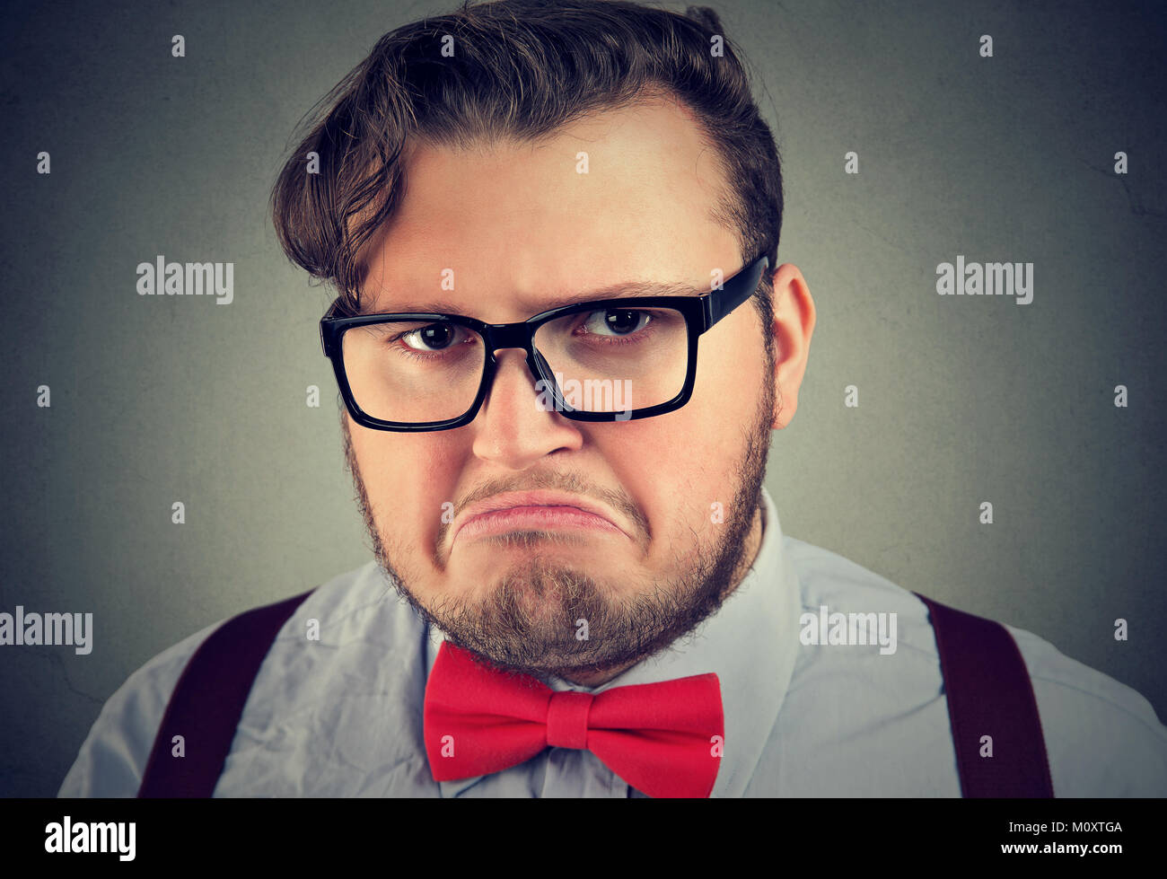 Ritratto di chunky uomo in occhiali cercando offeso e cupo che pongono alla fotocamera. Foto Stock