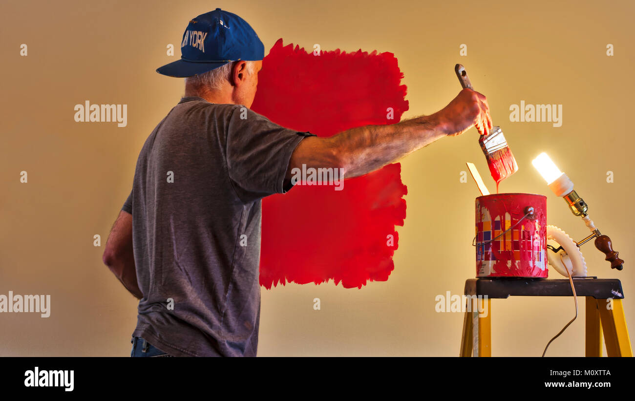 Un corso di laurea uomo pittura un muro nella sua casa. Foto Stock