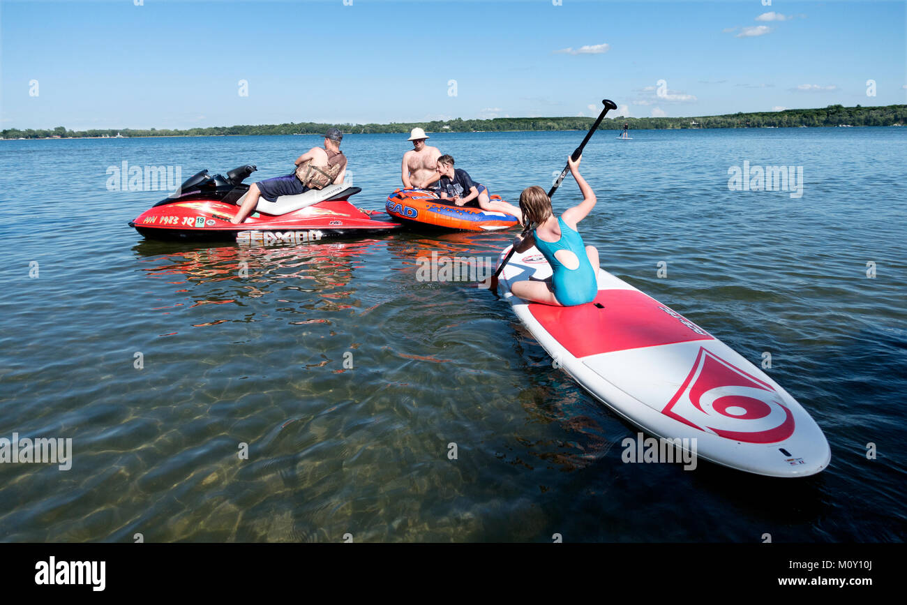 I bambini che si divertono sull'acqua a scopo ricreativo, paddleboard Seadoo e zattera gonfiabile. Clitherall Minnesota MN USA Foto Stock