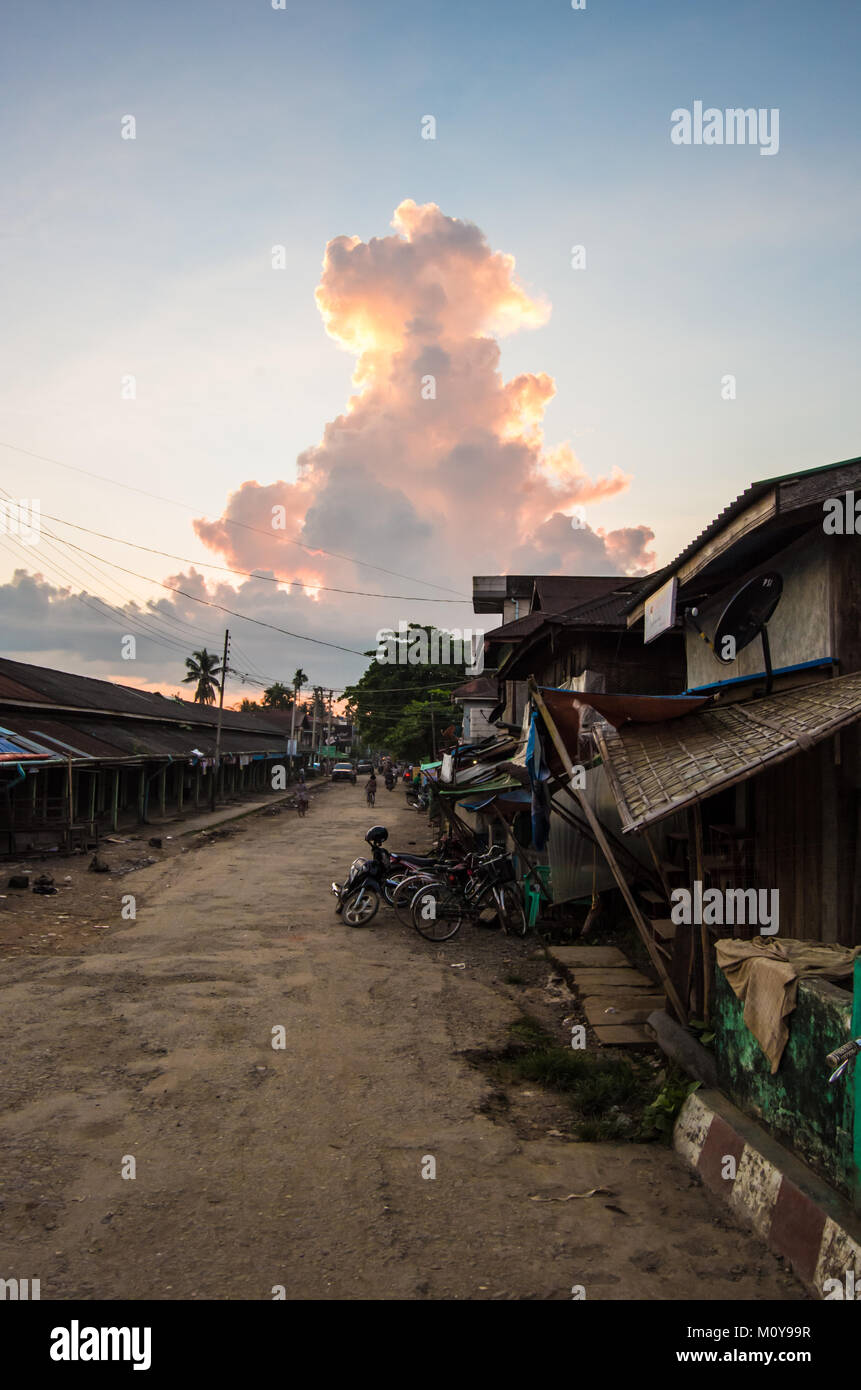 Un normale, strada sabbiosa con edifici shack offuscata da un enorme nuvola di monsone in Mrauk U, Stato di Rakhine, Myanmar Foto Stock