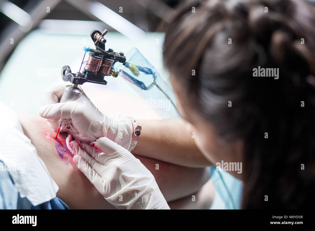 Bella dai capelli scuri tatuaggio donna artista il disegno di un tatuaggio per un tatuaggio, close-up, vista dal basso Foto Stock