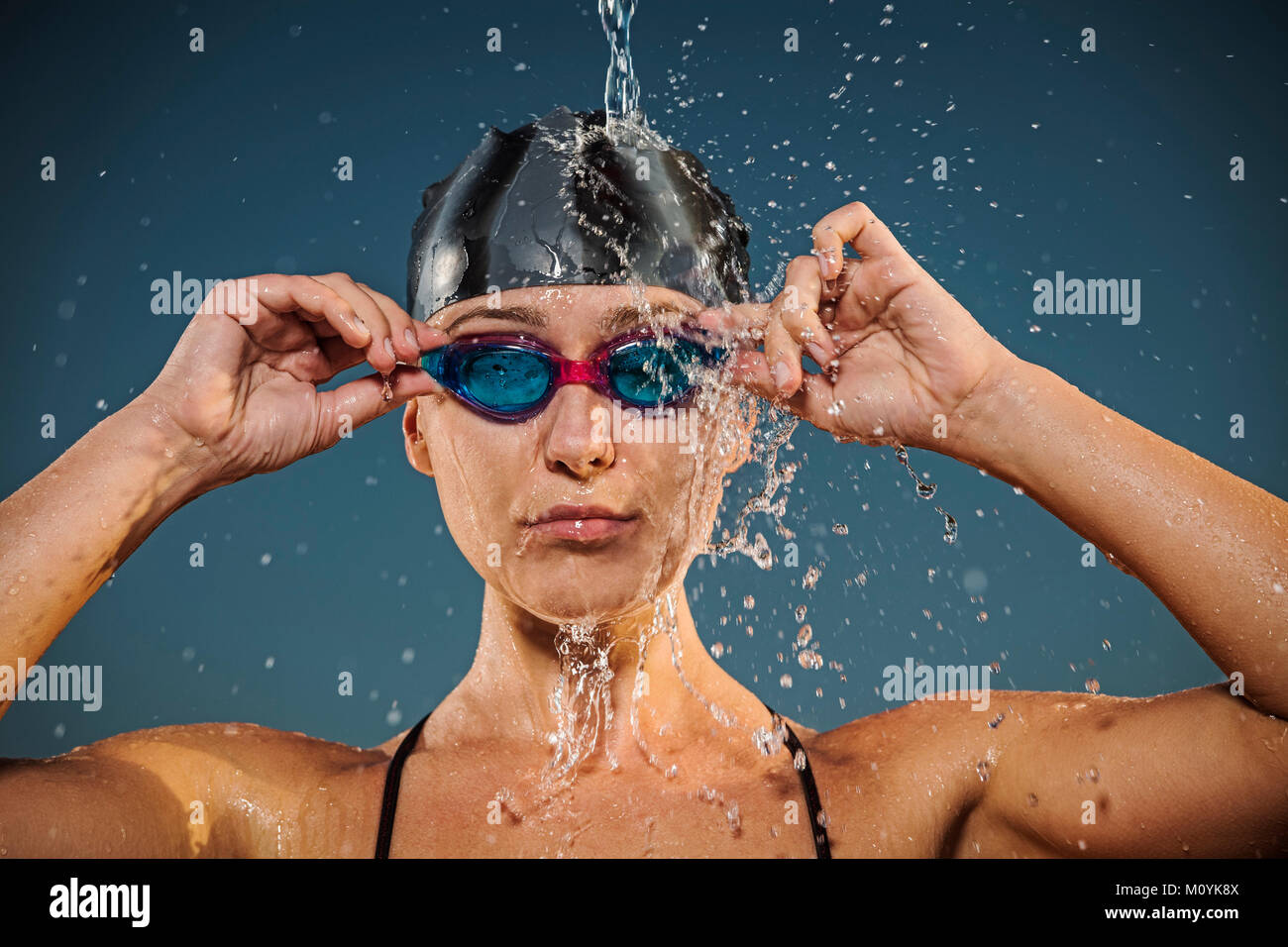 L'acqua spruzzata sulla donna caucasica regolando gli occhiali per nuoto Foto Stock