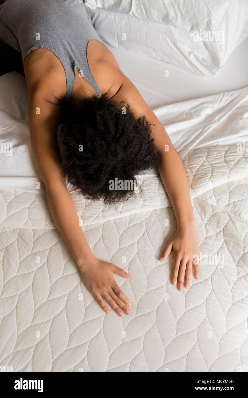 African American donna Stretching schiena sul letto Foto Stock