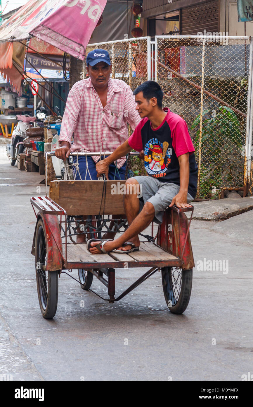 Uomo che cavalca il carrello verso il basso street, Mae Sot, Thailandia Foto Stock