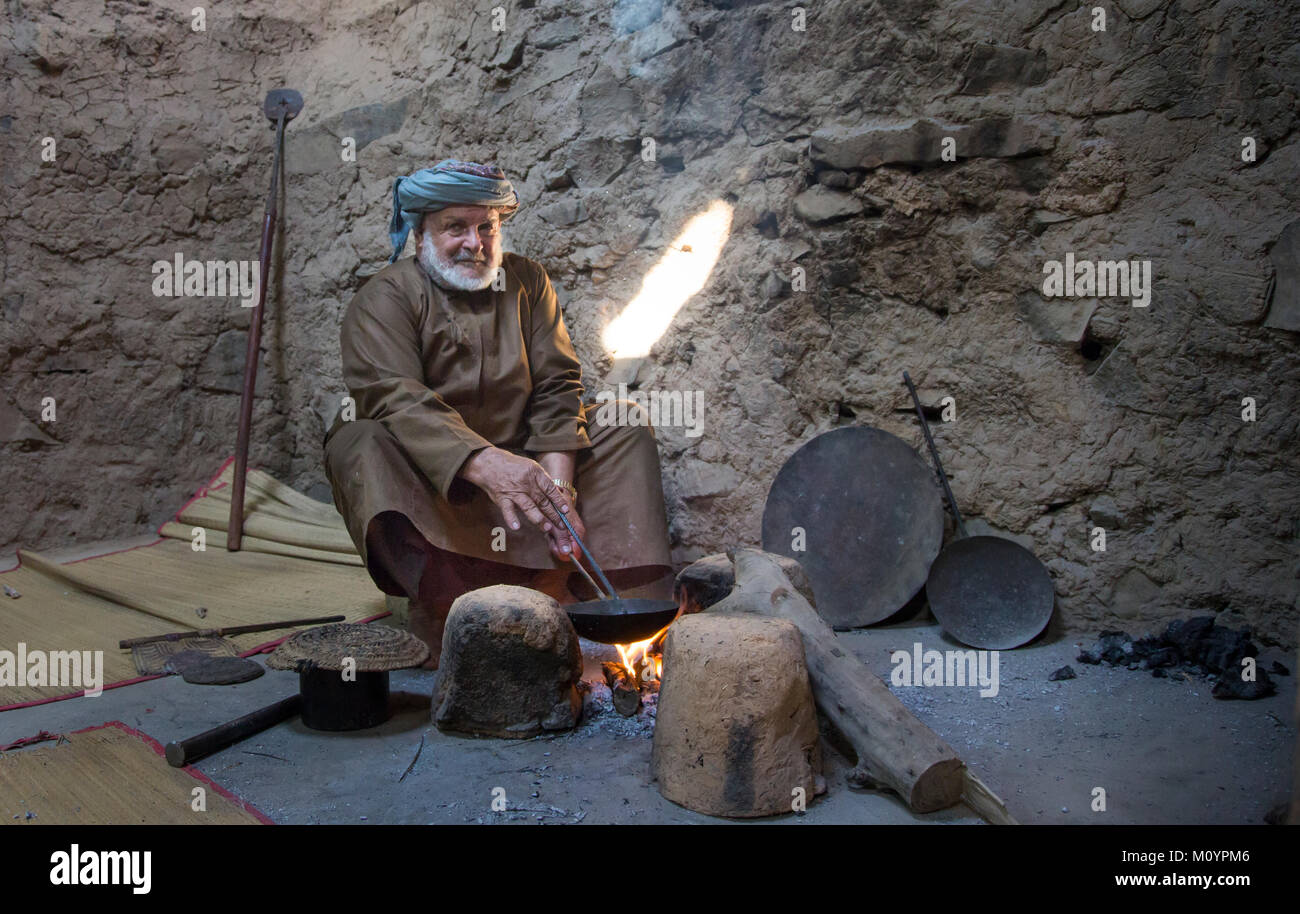 Nizwa, Oman, Dicembre 15th, 2016: Omani uomo torrefazione di caffè arabo in una casa tradizionale Foto Stock