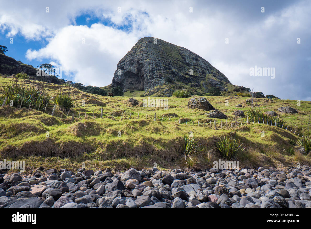 Moody nuvole sopra un picco roccioso e colline nella baia di acqueviti in Nuova Zelanda Foto Stock