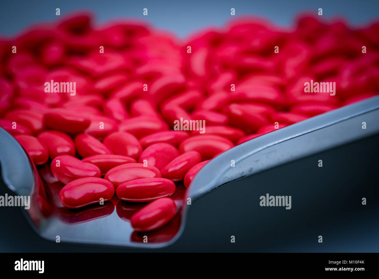 Macro shot dettaglio del rene rosso zucchero forma compressa rivestita pillole su acciaio inox vassoio di farmaco Foto Stock