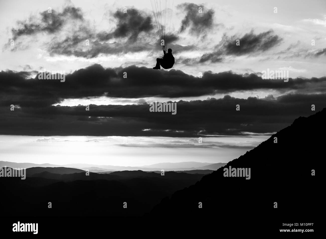 Bellissimo colpo di un parapendio silhouette volando sul Monte Cucco (Umbria, Italia) con il tramonto sullo sfondo Foto Stock
