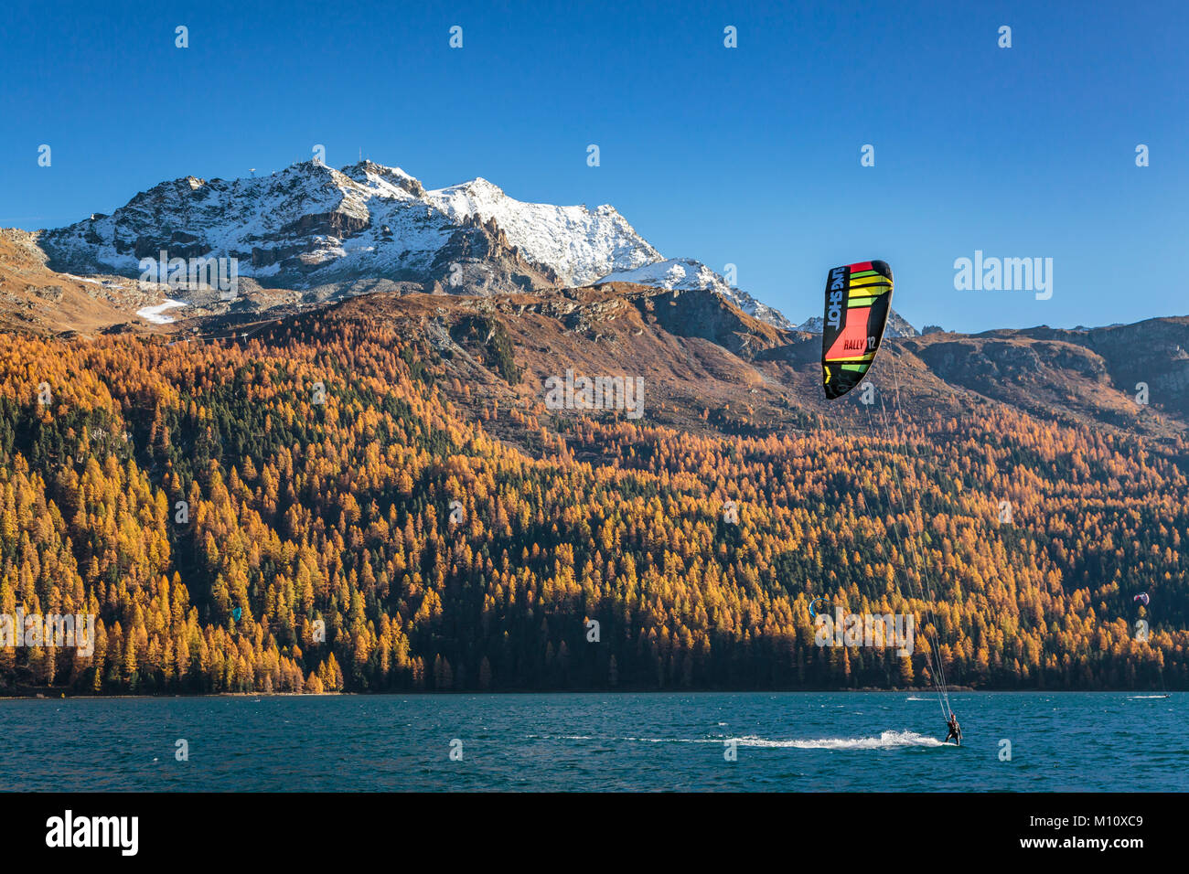 Wind surf sul lago di Silvaplana con la caduta delle foglie colore in larice alberi in Engadina, Graubuden, Svizzera, Europa. Foto Stock