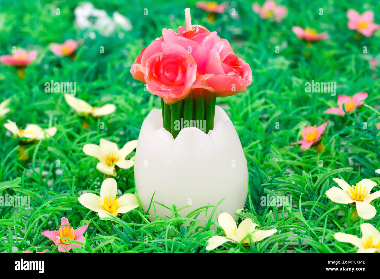 Uovo di Pasqua con fiore candela su erba articial sfondo. Foto Stock