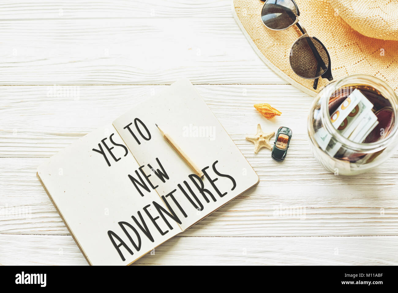 Nuova avventura testo concetto di segno. dire di sì a nuove avventure. Pianificazione viaggio estivo concetto e wanderlust. notebook jar denaro occhiali da sole hat gusci ca Foto Stock