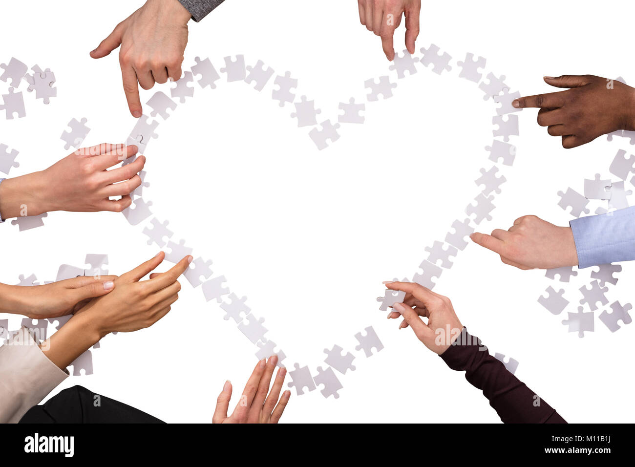 Gruppo di mani messa a forma di cuore con i puzzle su sfondo bianco Foto Stock