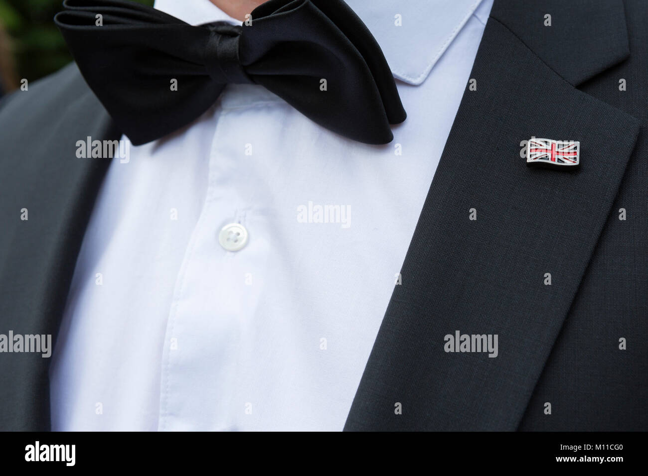 L uomo nella cena formale con il vestito nero farfallino e britannica Union Jack flag bavero badge Foto Stock