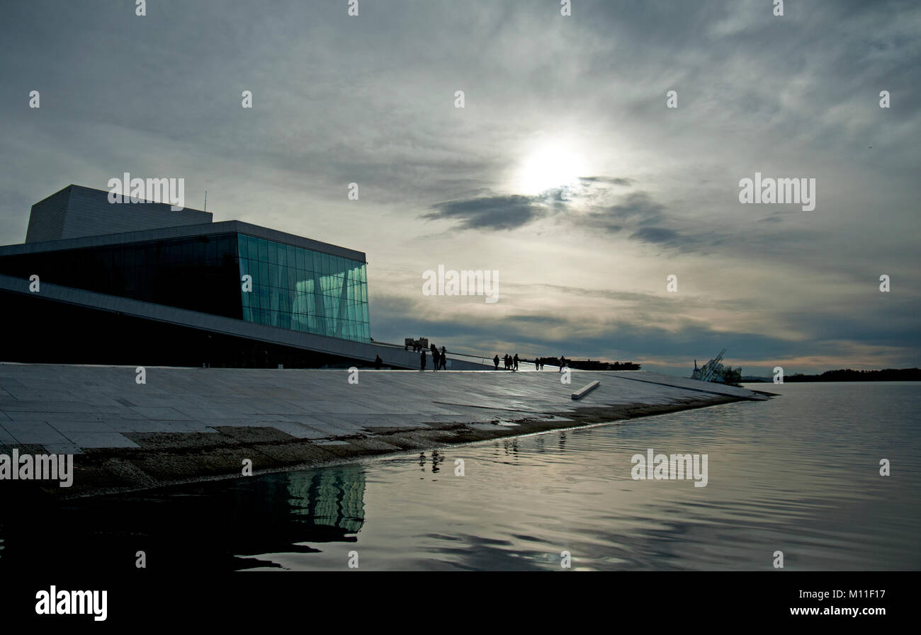 Vista al tramonto in tutta l'Oslofjord verso il marmo e granito concourse del vetro frontale Opera House di Oslo, Norvegia. Foto Stock