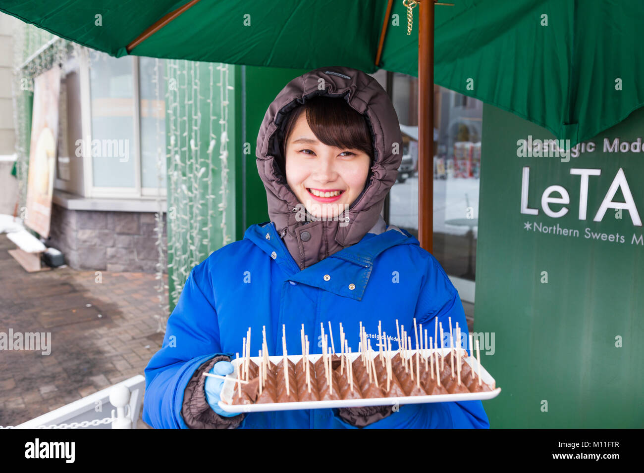 Otaru, Hokkaido, Giappone - 30 dicembre 2017, Felice donna giapponese in piedi di fronte a Le Tao, negozio di cioccolato, con vassoio di cioccolato di campioni per custom Foto Stock
